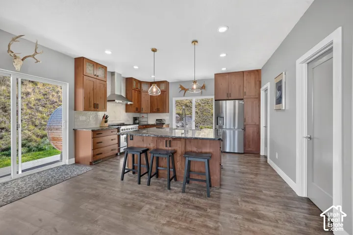 Gourmet kitchen featuring wood-finish cabinetry, stainless steel appliances, a center island with bar seating, and wood-finish flooring