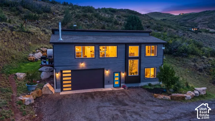 Contemporary exterior with dark siding, large windows, and a prominent garage door with horizontal glass panels