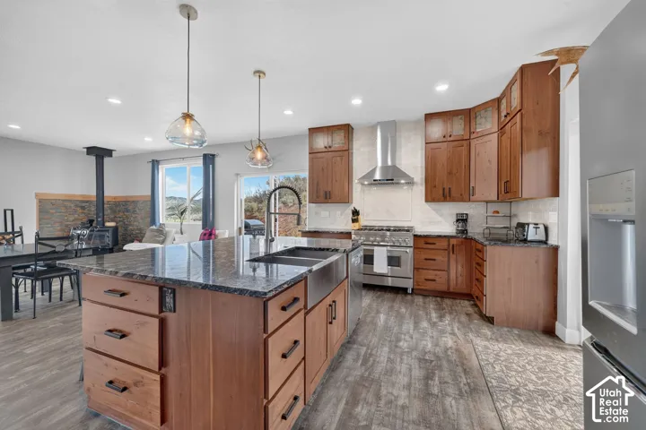 Kitchen featuring wood-finish flooring, dark stone countertops, stainless steel appliances, and wood cabinetry