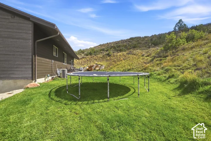 Expansive green lawn with a sloped natural landscape backdrop