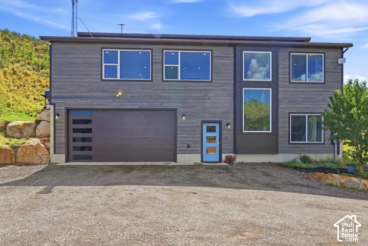 Modern exterior with horizontal siding, a prominent two-car garage with frosted glass inserts, a vibrant blue entry door, and large picture windows