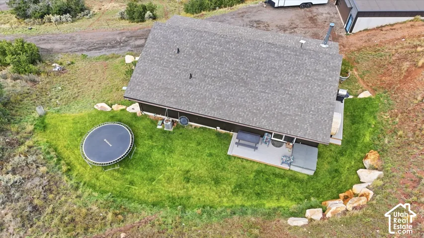 Asphalt shingle roof, outdoor patio, rock landscaping, and surrounding natural terrain