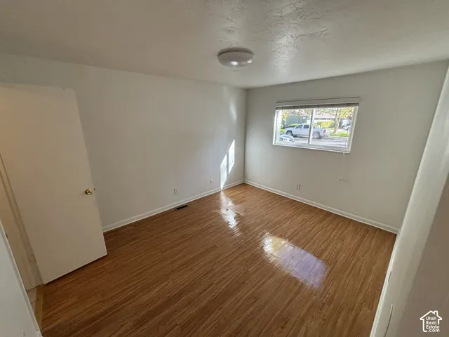 Wood-finish flooring, white walls, and a flush-mount ceiling light fixture