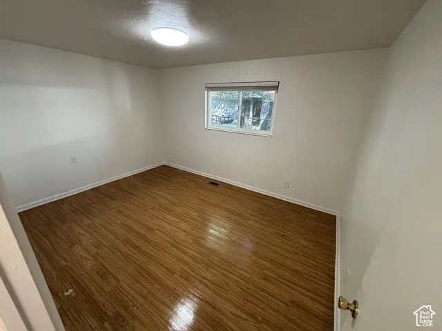 Bright room featuring wood-finish flooring, white walls, and a recessed window