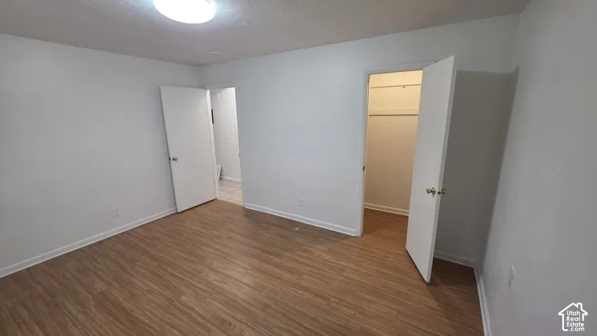Wood-finish flooring with white walls and a ceiling-mounted light fixture