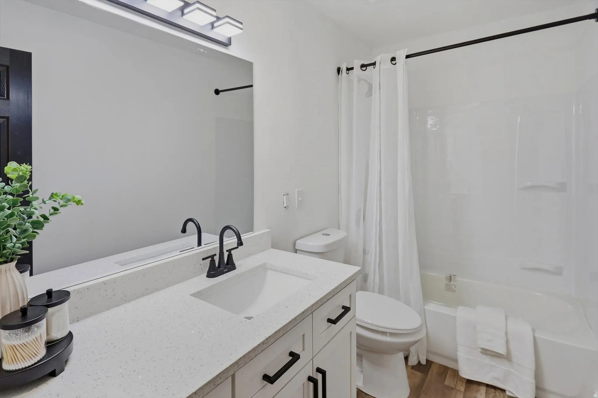 Bathroom featuring a white vanity with a light-toned countertop, rectangular undermount sink, and matte black hardware
