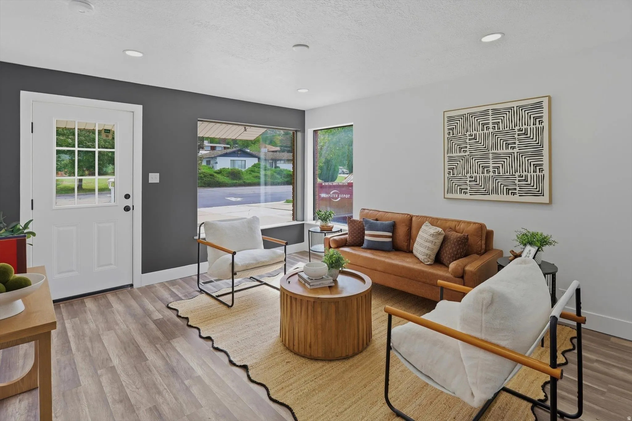 Recessed lighting, wood-finish flooring, white panel door with windows, large picture window, and contrasting wall colors