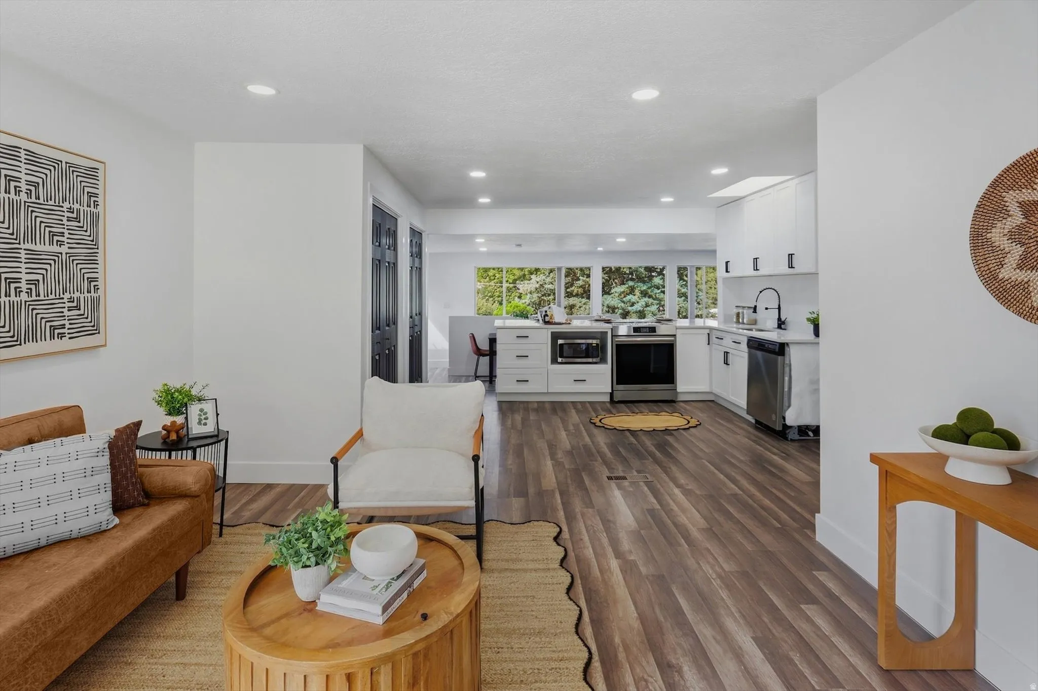Open-concept living space with wood-finish flooring, recessed lighting, and white walls