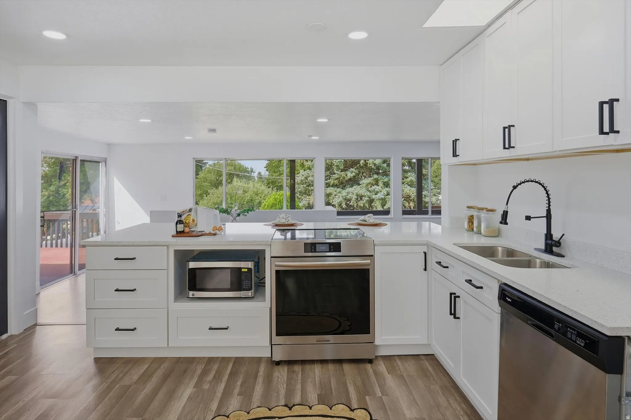 White cabinetry and light-toned countertops with a stainless steel range, sink, and dishwasher