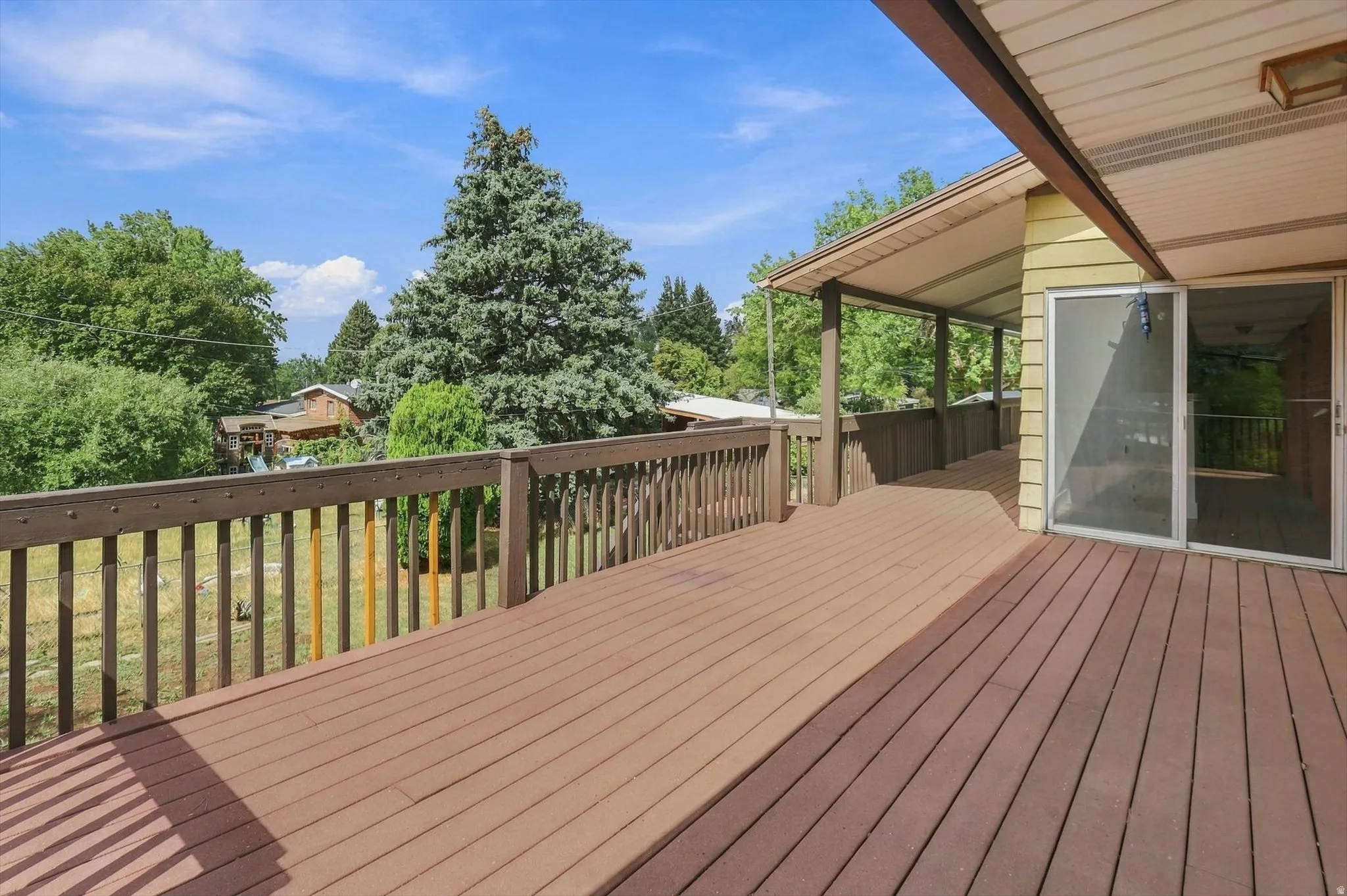 Expansive outdoor deck with wood-finish flooring, a wood railing, and a covered section