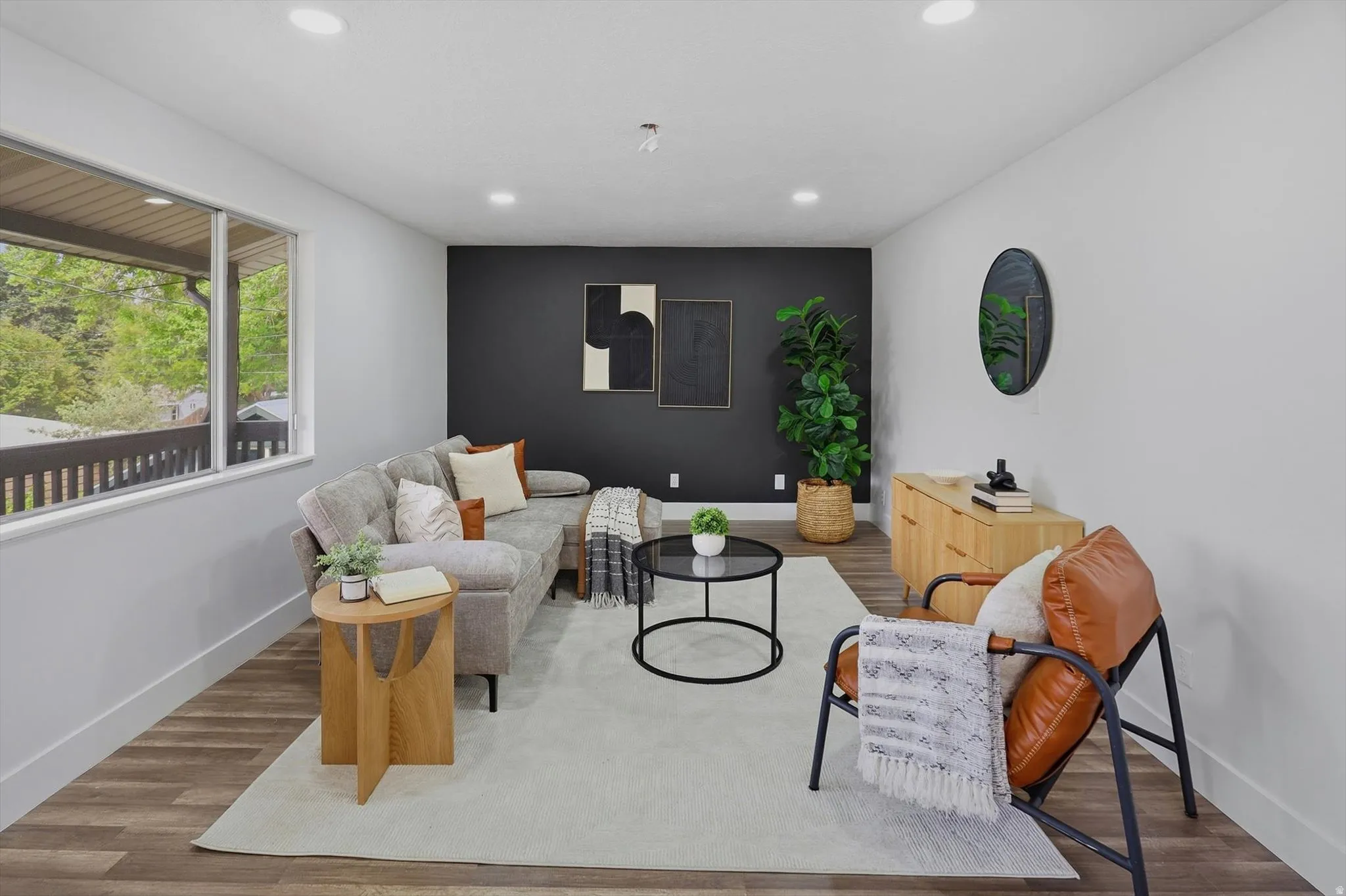 Recessed ceiling lighting, wood-finish flooring, accent wall, white window trim, and a built-in wood-tone cabinet