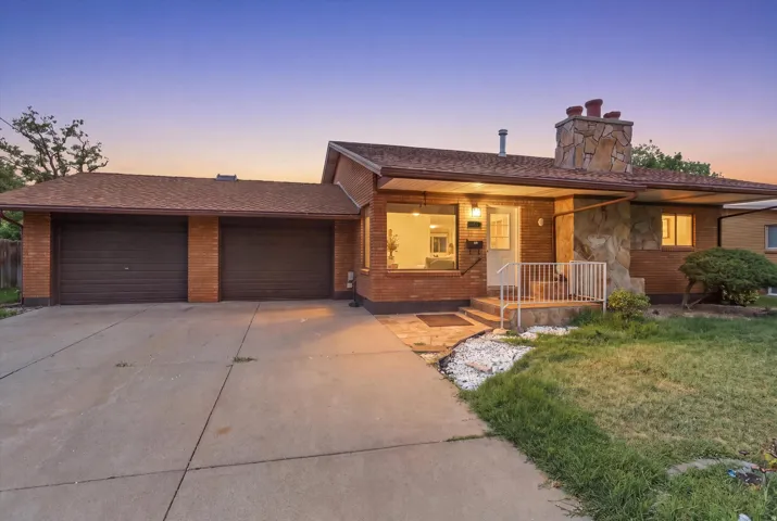 Brick exterior with stone accents, covered front entry, attached two-car garage, and concrete driveway