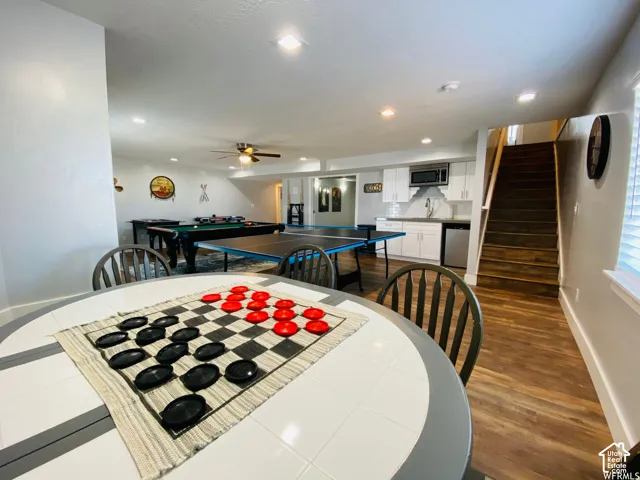 Spacious recreational area featuring wood-finish flooring, recessed lighting, and a built-in wet bar with white cabinetry
