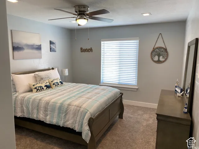 Plush carpeting, window with blinds, recessed lighting, ceiling fan with integrated lighting, and a built-in dresser with mirror