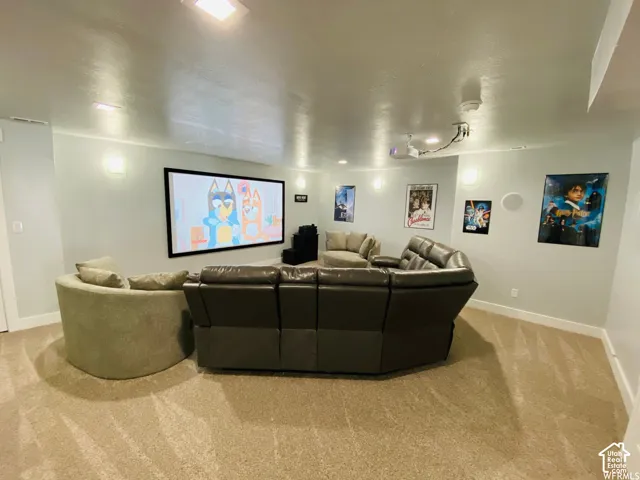 Wall-mounted projection screen, recessed ceiling lighting, wall-mounted sconces, and neutral-toned carpeting