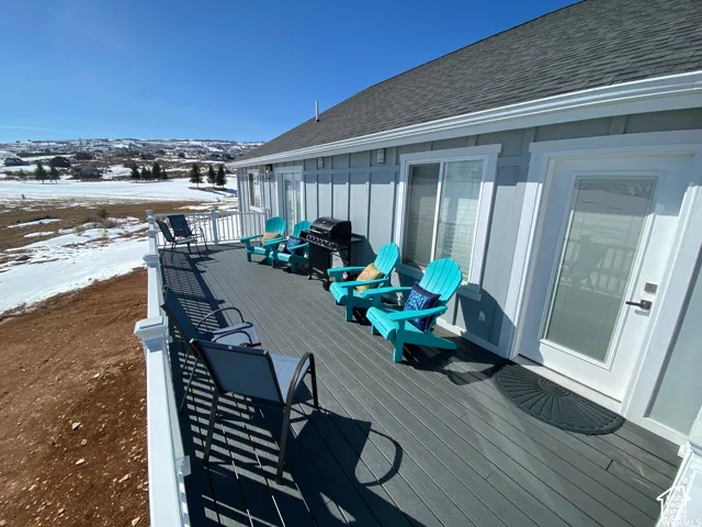 Expansive deck with composite decking and white railing, featuring sliding glass doors and a glass-paneled exterior door