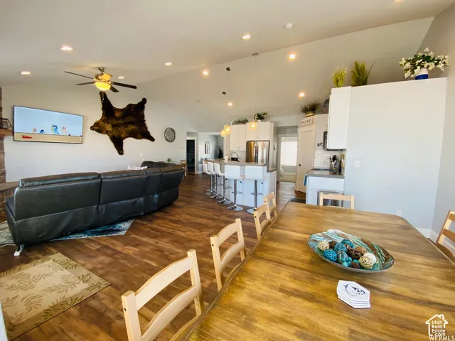 Vaulted ceiling with recessed lighting, wood-finish flooring, and white kitchen cabinetry