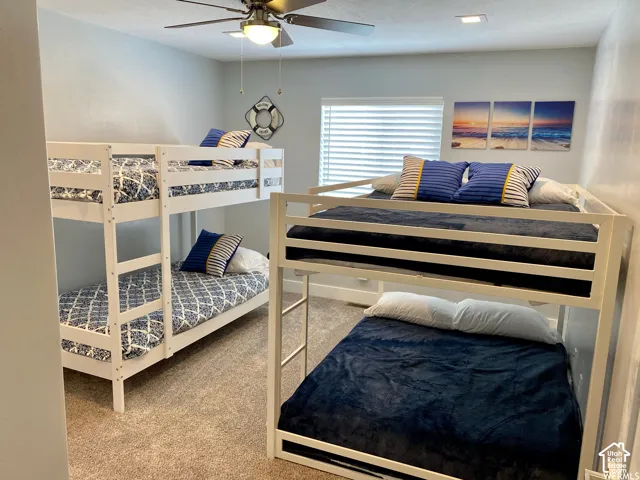 Carpeted room featuring two white-finished bunk beds, a ceiling fan, recessed lighting, and a window with blinds