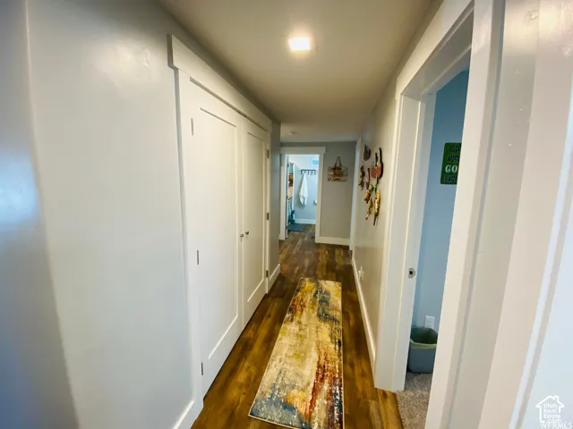 Hallway with wood-finish flooring, white trim, and light-toned walls