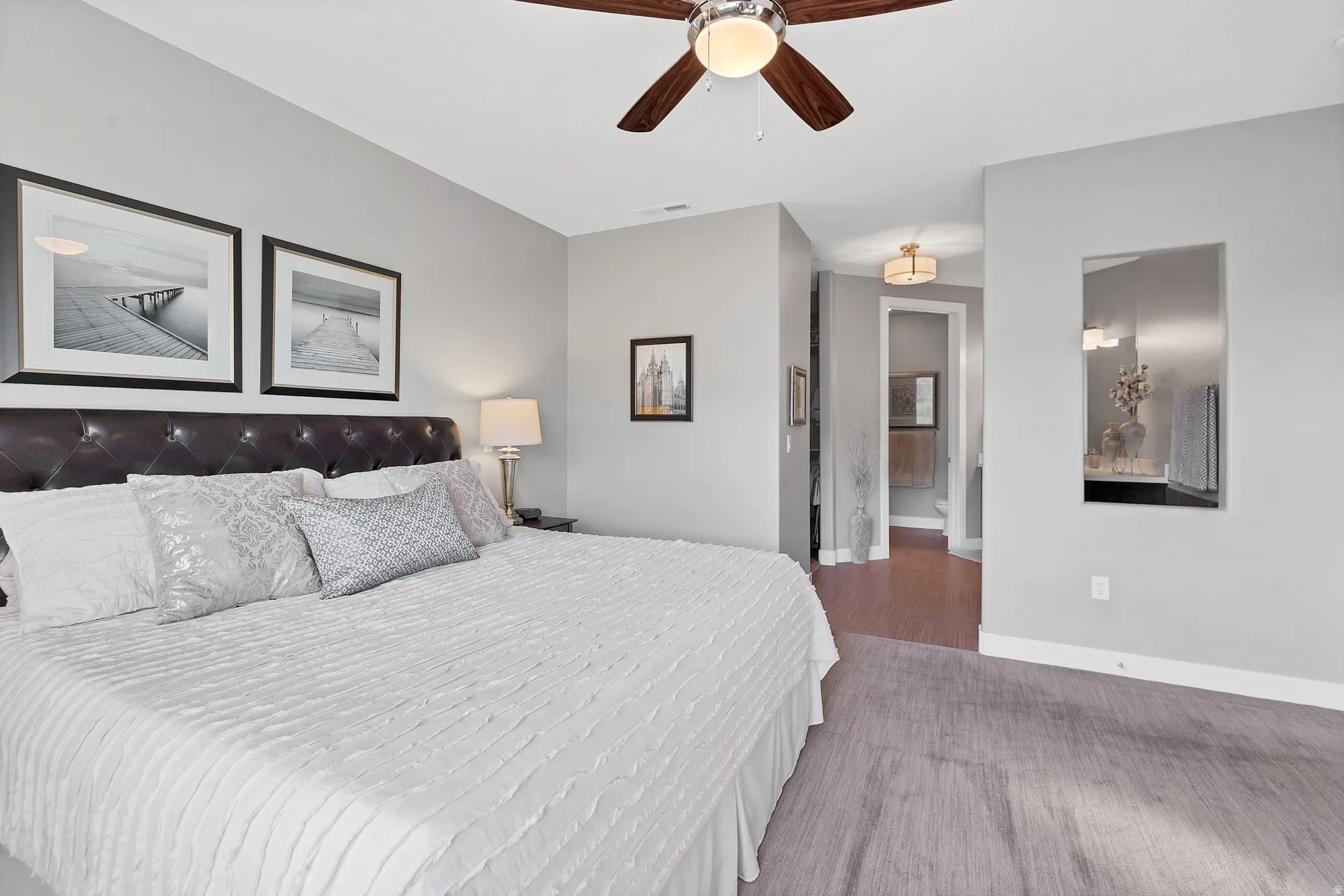 Wall-mounted mirror, ceiling fan with light fixture, recessed lighting, and a neutral color palette