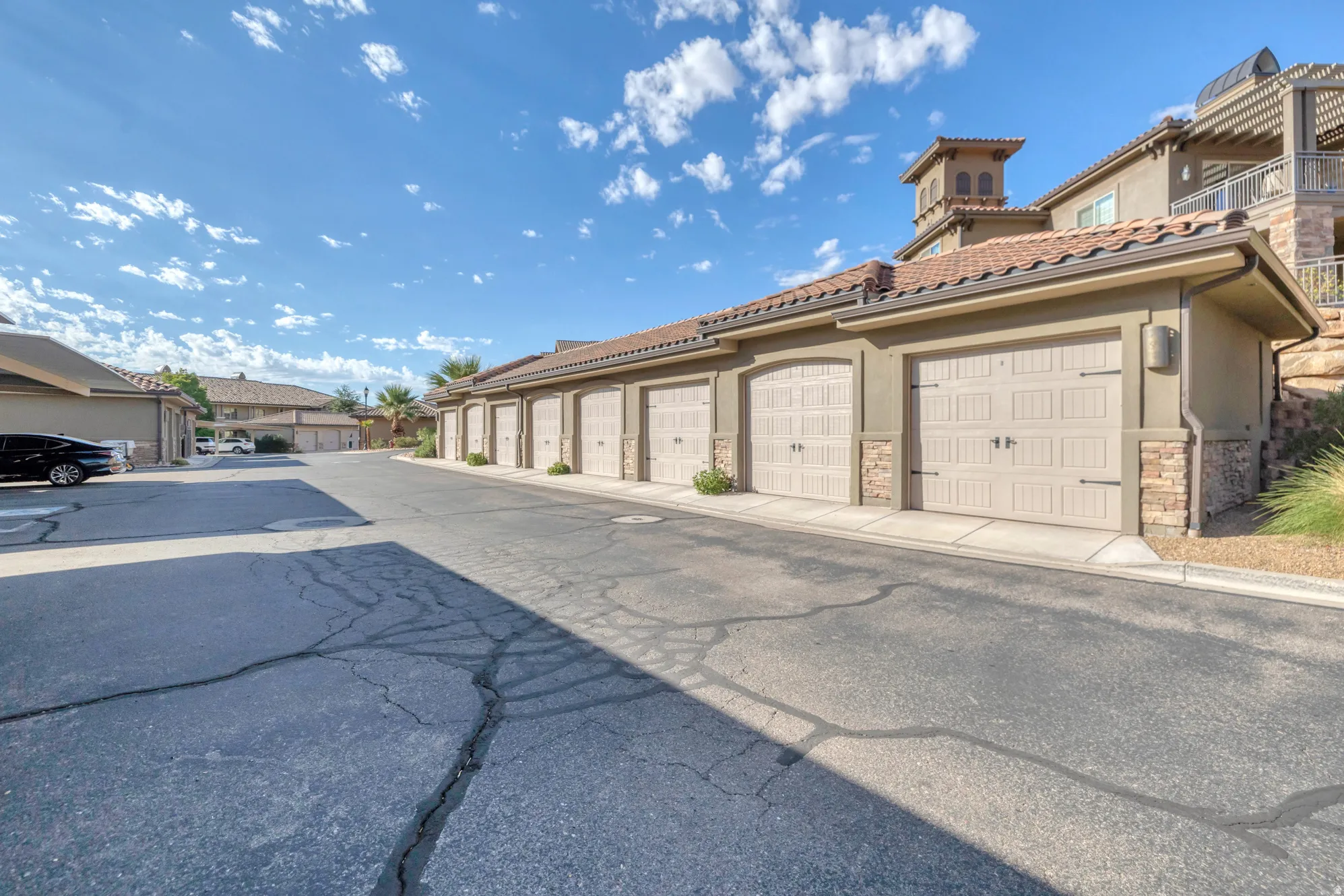 Individual garages featuring decorative doors, stone accents, and exterior lighting fixtures