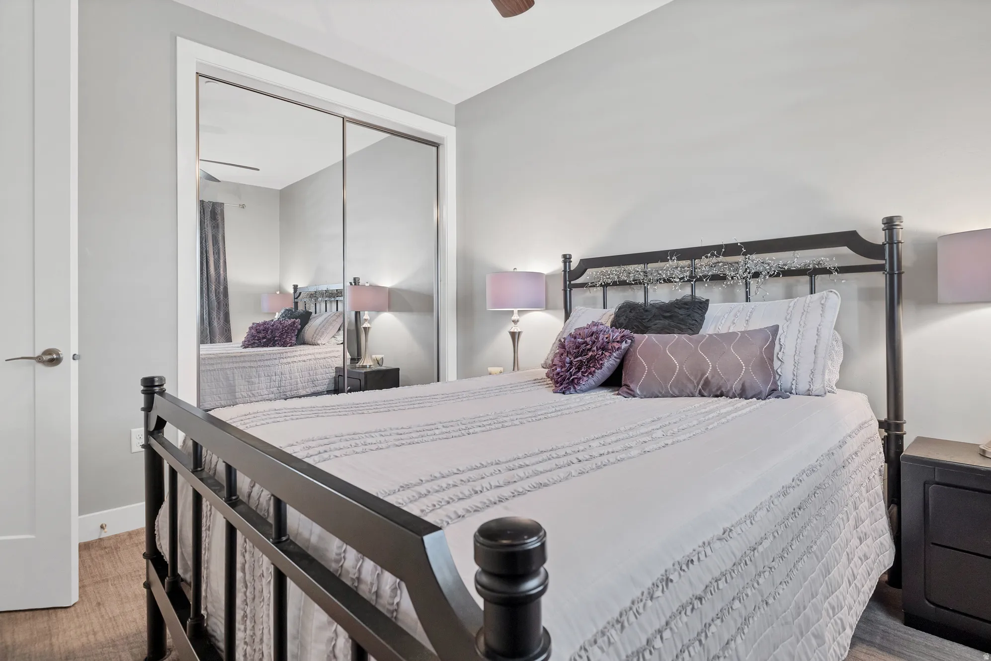 Mirrored closet doors, light gray wall paint, white trim, wood-finish flooring, and a ceiling fan