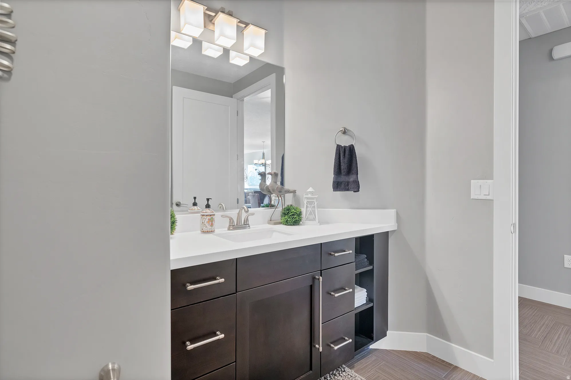 Vanity with an integrated sink, dark wood-finish cabinetry, and brushed nickel hardware