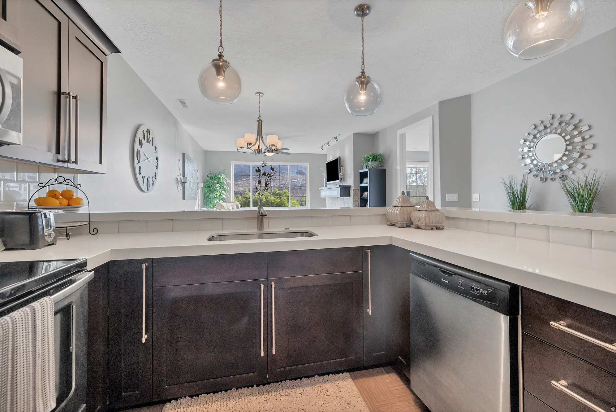 Kitchen featuring dark wood-finish cabinetry, light countertops, subway tile backsplash, and stainless steel appliances