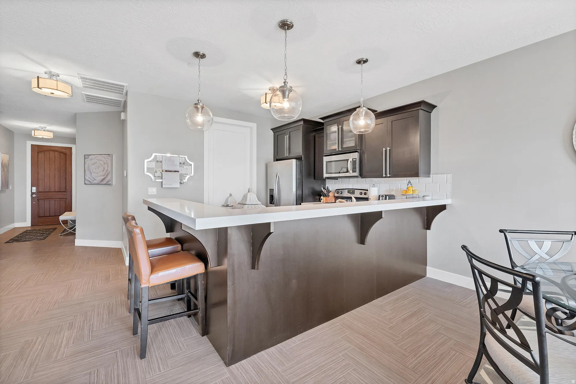 Kitchen island with a white countertop and dark cabinetry, stainless steel appliances, and a subway tile backsplash
