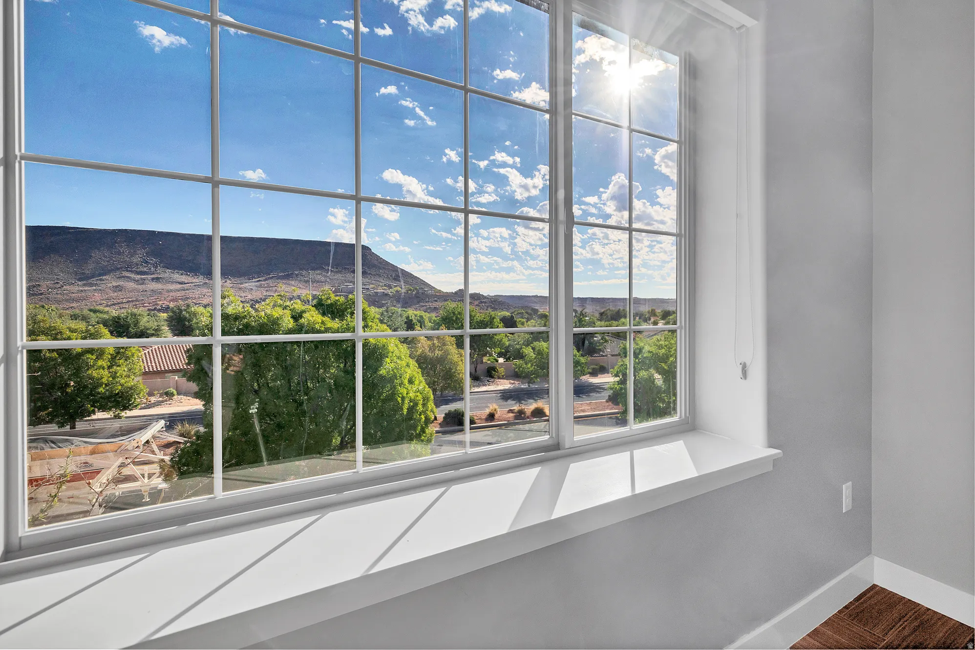 Expansive window with grid panes, offering a broad scenic backdrop of distant mountains and surrounding greenery