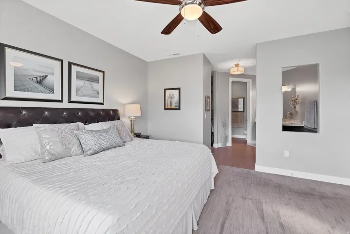 Wall-mounted mirror, ceiling fan with light fixture, recessed lighting, and a neutral color palette