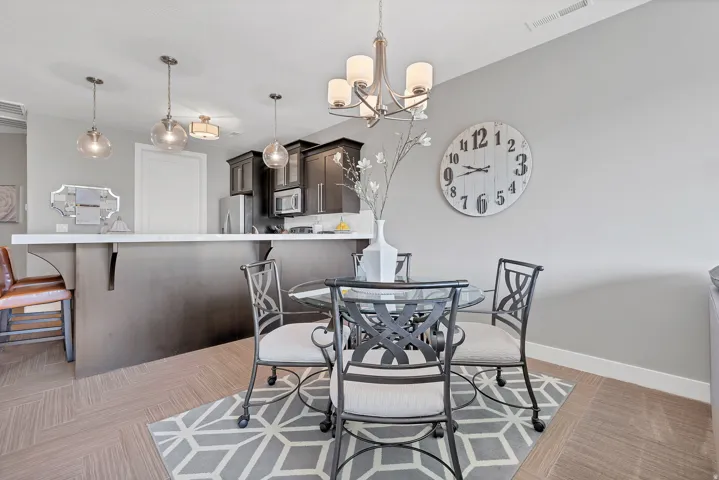 Open-concept dining area with wood-finish flooring, a contemporary chandelier, and a breakfast bar with pendant lighting