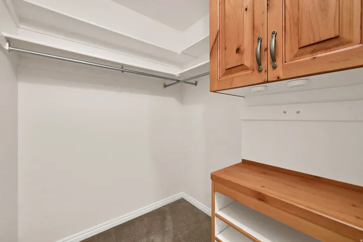 Built-in wood-finish cabinetry with brushed nickel hardware, integrated lighting, and open shelving