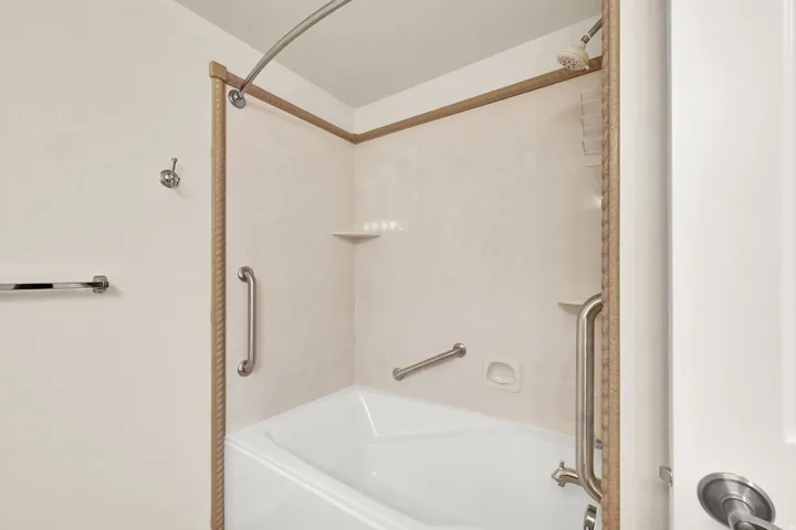 Bathtub with shower fixture, integrated shelving, and grab bars