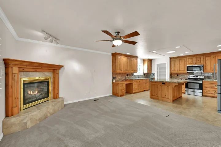 Wood-finish cabinetry, stainless steel appliances, and a central island with countertop seating define the kitchen