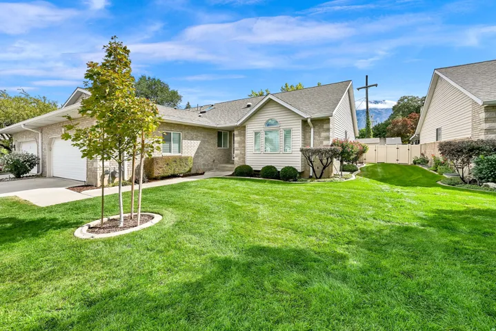 Brick and siding exterior with a pitched roof, featuring a two-car garage, established landscaping, and a manicured lawn