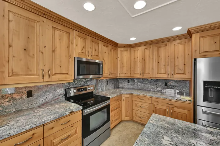 Wood cabinetry paired with stone countertops and a coordinating backsplash