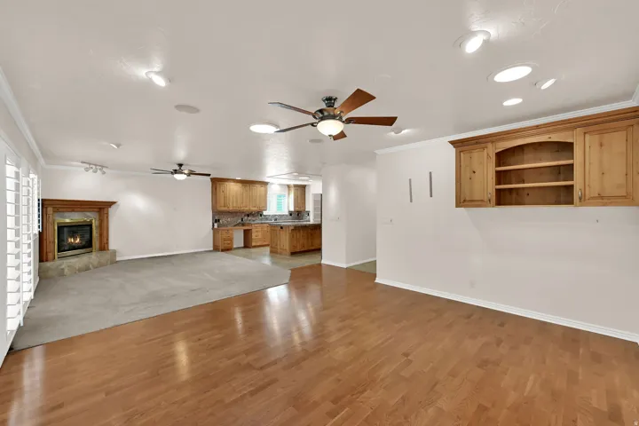 Hardwood flooring, recessed lighting, ceiling fans, built-in cabinetry, and a fireplace with a stone hearth