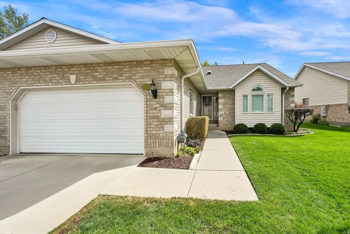 Light brick exterior with siding accents, attached garage, concrete driveway, and front walkway