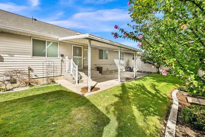 Covered patio space, concrete steps with handrail, sliding glass door, siding exterior, and landscaped perimeter