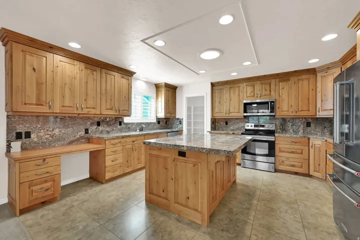 Kitchen featuring light wood cabinetry, stone countertops, stainless steel appliances, a center island, and recessed lighting