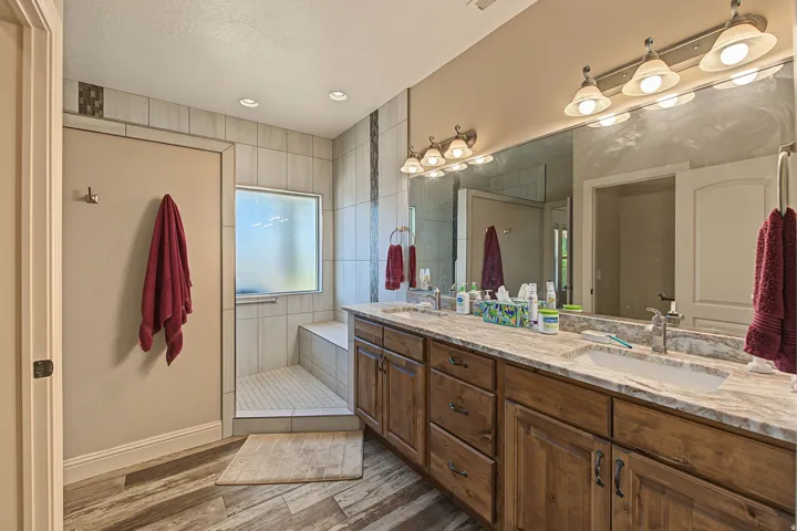 Dual vanity with integrated sinks, stone-finish countertop, and wood-finish cabinetry