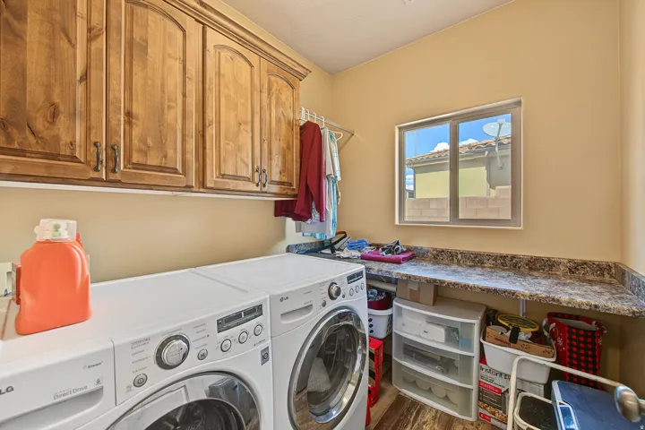 Laundry area featuring wood-finish cabinetry, ample countertop space, a window, and wood-look flooring
