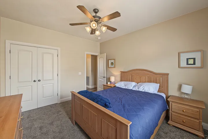 Carpeted flooring, neutral wall tones, white panel doors, and a ceiling fan with integrated lighting