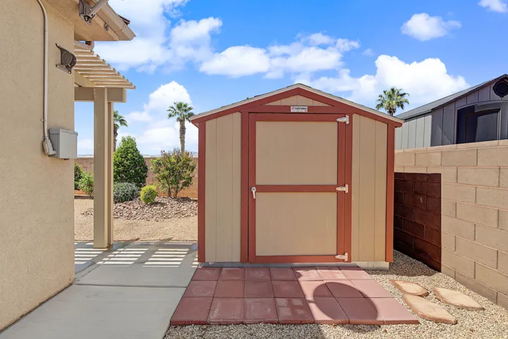 Freestanding shed with a gable roof, concrete walkway, and block wall fencing