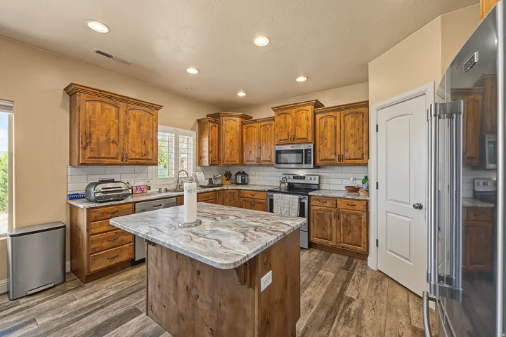 Wood-finish flooring, recessed lighting, wood cabinetry, granite countertops, and stainless steel appliances