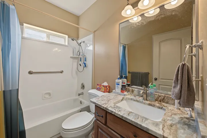 Bathroom featuring a vanity with an integrated sink, granite-style countertop, and wood-finish cabinetry