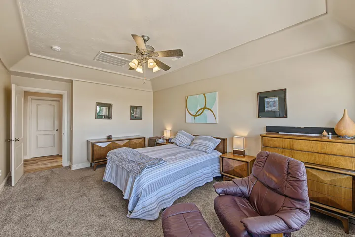 Tray ceiling with recessed lighting, ceiling fan with integrated lighting, neutral-toned walls, and plush carpeting
