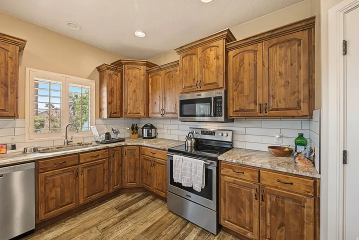 Wood-finish flooring with a U-shaped kitchen layout, featuring wood cabinetry and light-toned countertops