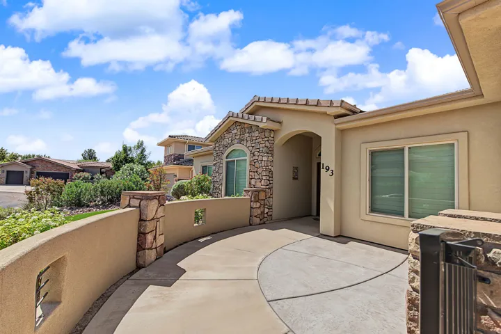 Stucco exterior with stone accents, arched entryway, and a curved concrete driveway
